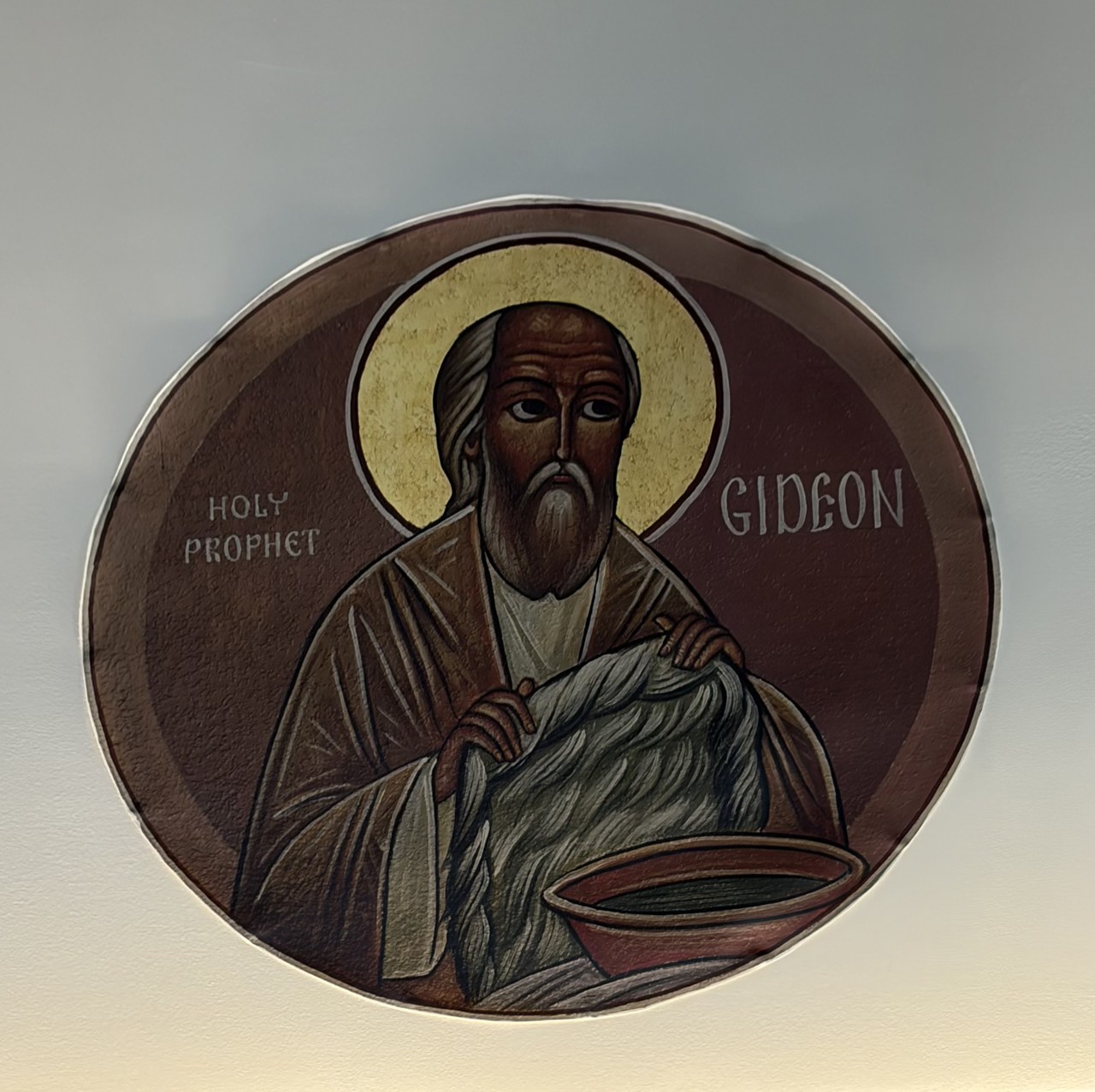 Circular church icon of the prophet Gideon holding a fleece, with a golden halo.